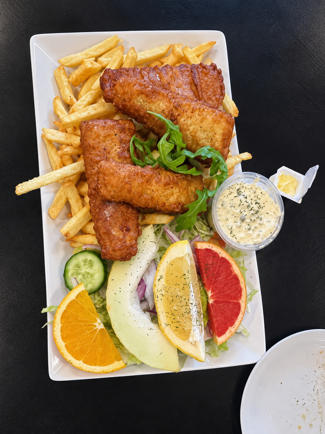 Fisk och chips serverat med sallad, citron och sås
